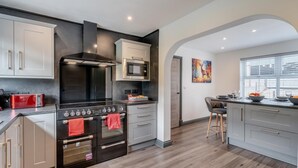 A modern kitchen with a central island, stainless steel appliances, and a microwave. - 3 Bed in Cockermouth (oc-o31515) (Setmurthy)