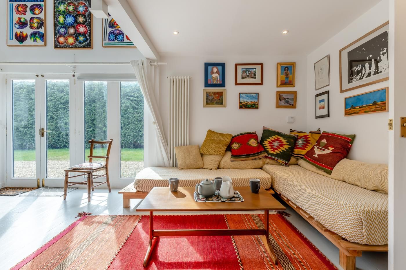 A living room with a sofa, a coffee table, and a chair. There are framed pictures on the walls and a view through the glass doors.