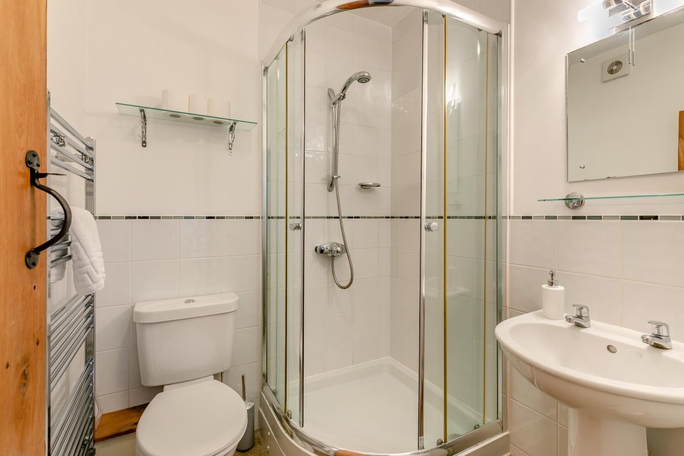 Une salle de bain moderne avec une douche à parois de verre, des toilettes, un lavabo et un miroir.