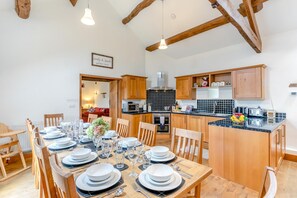 A dining area with a wooden table set for six, kitchen cabinets, and a view into a living room. - 5 Bed in Litton (oc-l31793) (Litton)