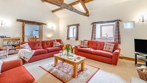 Un salón amplio con dos sofás rojos, una mesa de centro de madera y un televisor.