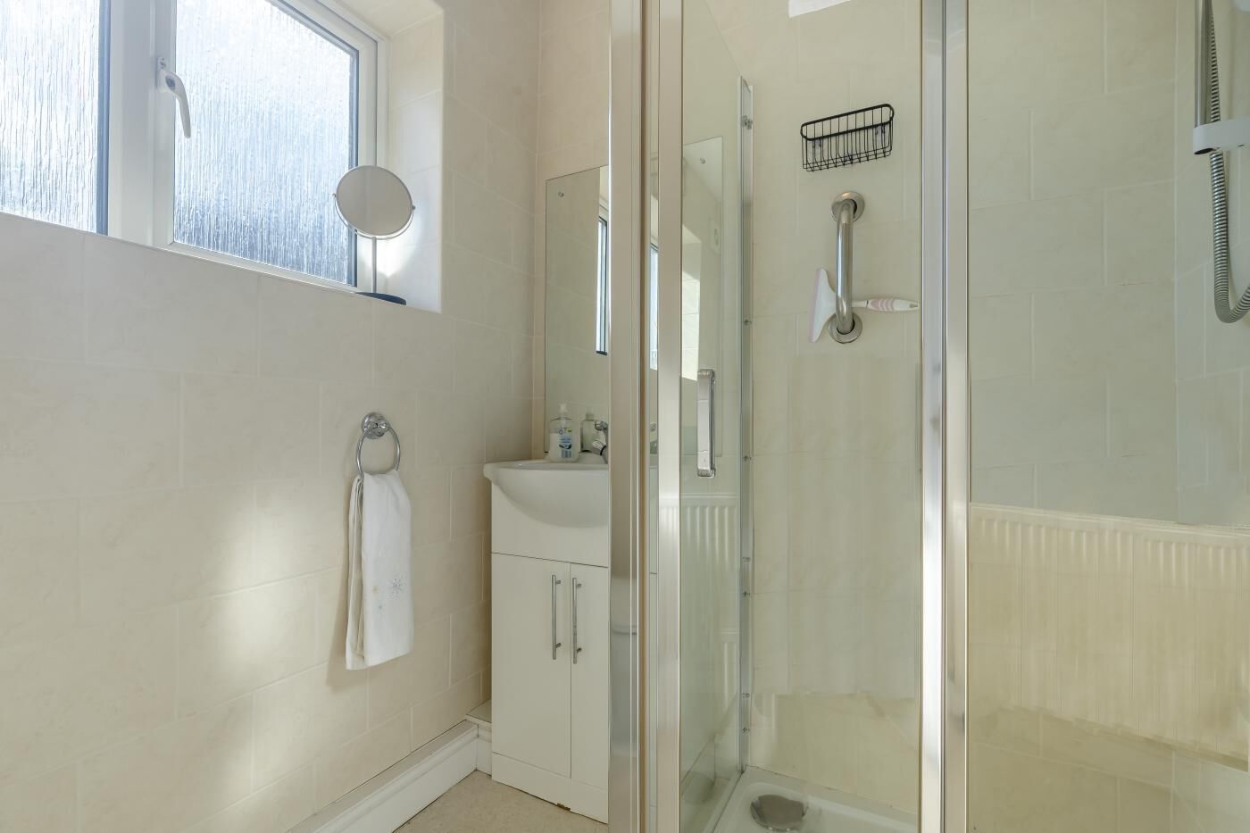 Une salle de bain avec une douche à parois de verre, un lavabo avec un miroir et un porte-serviettes.