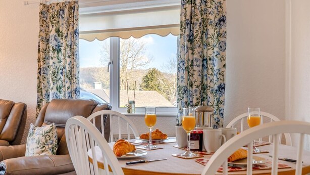 Een ontbijtruimte met een gedekte tafel, inclusief croissants, sapglazen en een koffiepot.