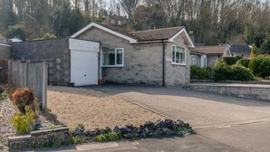 Een gelijkvloers huis met een witte garage, een gevel van natuursteen en een verharde oprit.