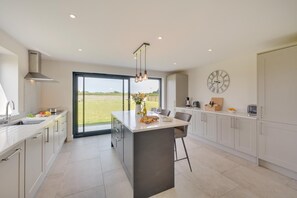 A modern kitchen with a large island, a built-in oven, and a view of the outdoors.