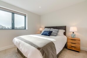Une chambre à coucher avec un grand lit, des tables de chevet et une fenêtre.