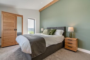 A bedroom with a bed, nightstands, a wooden wardrobe, and a window.