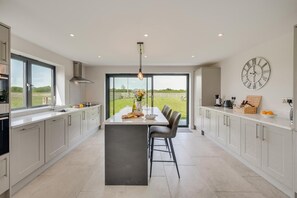 A modern kitchen with a central island, large windows, and a view of the outdoors. - 4 Bed in Crosby (oc-b31135) (Northallerton)