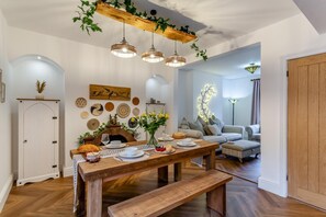 Ein Essbereich mit Holztisch, gedeckt für eine Mahlzeit, umgeben von einer Couch und einem Kamin.
