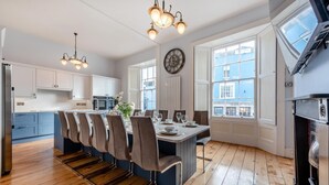 Una cocina moderna con comedor, ventanas amplias y un reloj en la pared.
