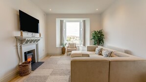 A living room with a fireplace, sofa, and television. - 4 Bed in St. Ives (oc-p31118) (Saint Ives)