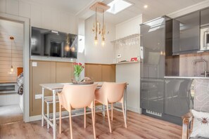 A modern kitchen with a dining area, a built-in oven, and a TV. - 2 Bed in Newport (oc-f31127) (Newport)