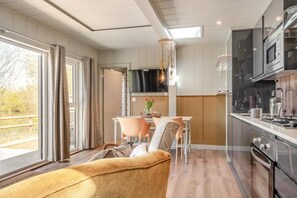 Eine moderne Küche mit Einbauofen, ein Essbereich mit Tisch und Stühlen sowie ein großes Fenster mit Blick ins Freie.