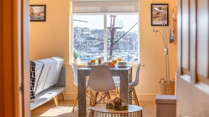 A dining area with a table set for two, a bench, and a view of the cityscape through a large window. - 2 Bed in Whitby (oc-h31801) (Whitby)