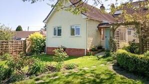 Ett enplanshus med ett tak täckt av tegelpannor, en veranda och en välskött trädgård.