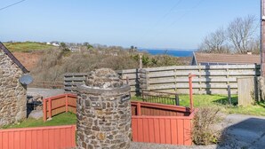 A stone structure with a sign reading "Woodlands," a wooden fence, and a view of the sea in the background. - 2 Bed in Little Haven (oc-i31766) (Little Haven)