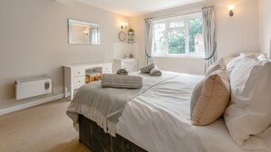 Ein Schlafzimmer mit Bett, Kommode, Spiegel, Fenster und Heizkörper.