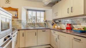 A kitchen with beige cabinets, a built-in oven, a sink, and a window with a view of a house. - 3 Bed in Windermere (oc-b31667) (Crook)