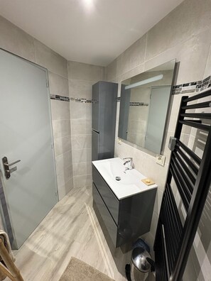 A modern bathroom with a white sink, dark cabinet, and a large mirror. - Spacious T3 in Grau-du-Roi, secure residence near beach and town center (Le Grau-du-Roi)