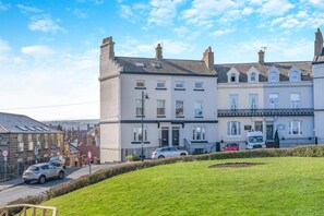 A multi-story residential building with a flat roof, a front entrance, and a small garden area. - 2 Bed in Whitby (oc-e31738) (Whitby)