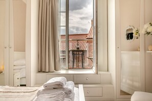 A bedroom with a large window, a bed with white linens, a bedside table, and a dresser. - 2 Bed in Whitby (oc-e31738) (Whitby)