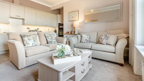 Sala de estar com dois sofás, uma mesa de centro e uma cozinha ao fundo.