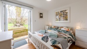 Ein Schlafzimmer mit Bett, Nachttisch, Fenster und Tür.