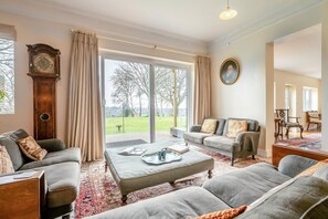 A spacious living room with a large window, a classic wooden clock, and a cozy sofa set. - 5 Bed in Battle (oc-c31779) (Battle)