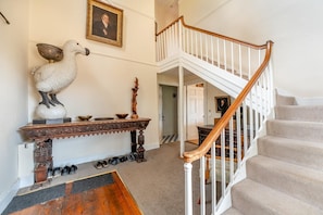 A staircase with a wooden handrail and white balusters, a white wall with a framed portrait, and a wooden console table with a white bird sculpture and various bowls. - 5 Bed in Battle (oc-c31779) (Battle)