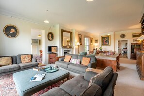 A spacious living room with a sofa set, a coffee table, and a fireplace. There is a dining area with a table and chairs visible in the background. - 5 Bed in Battle (oc-c31779) (Battle)