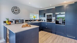Una cocina moderna con armarios oscuros, una isla central y un reloj de pared grande.