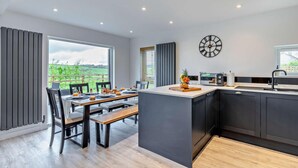 Una cocina moderna con una isla central, un comedor con vistas y un reloj en la pared.
