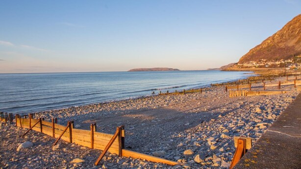A rocky beach with wooden barriers and a clear view of the sea. - 1 Bed in Llanfairfechan (oc-t31122) (Llanfairfechan)