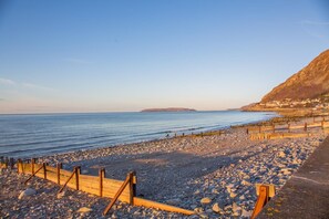 Una playa rocosa con barreras de madera y una vista despejada del mar.