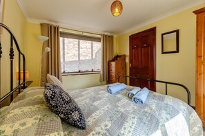A bedroom with a bed, a window with curtains, a wooden wardrobe, and a door. - 2 Bed in Llangorse (oc-p31754) (Llangorse)