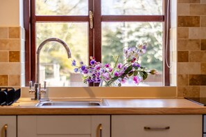 Une cuisine avec une fenêtre, un évier et un vase rempli de fleurs.