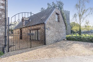 A stone building with a metal gate, a small window, and a gravel driveway. - 2 Bed in Llangorse (oc-p31754) (Llangorse)