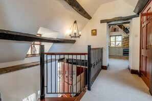 A staircase with a wooden handrail, a black metal railing, and a chandelier.