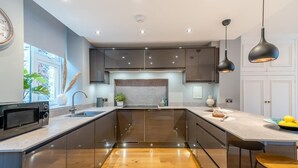A modern kitchen with a central island, stainless steel appliances, and pendant lighting. - 4 Bed in Windermere (oc-o31130) (Windermere)