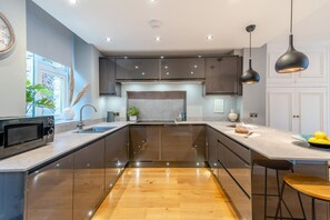 A modern kitchen with a central island, stainless steel appliances, and pendant lighting. - 4 Bed in Windermere (oc-o31130) (Windermere)