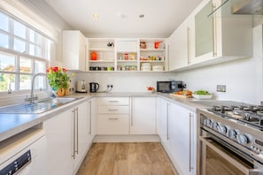 A modern kitchen with white cabinetry, a stainless steel range hood, and a built-in oven. - 2 Bed in Dalmally (oc-m31803) (Cladich)