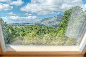 Une vue à travers une fenêtre sur un paysage verdoyant et luxuriant, avec une montagne en arrière-plan.