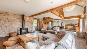 A cozy living room with a stone wall, a fireplace, a sofa set, and a staircase leading to an upper level. - 2 Bed in St. Davids (oc-t31868) (St Davids)