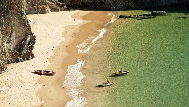 A beach with kayaks and a canoe, clear water, and rocky cliffs. - 2 Bed in St. Davids (oc-t31868) (St Davids)