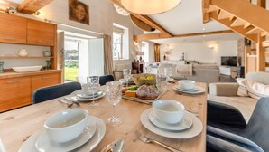 A dining area with a wooden table set for a meal, surrounded by chairs. - 2 Bed in St. Davids (oc-t31868) (St Davids)