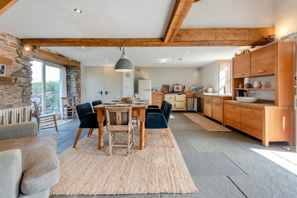 A spacious kitchen with wooden cabinets, a dining area with a large table and chairs, and a stone wall.