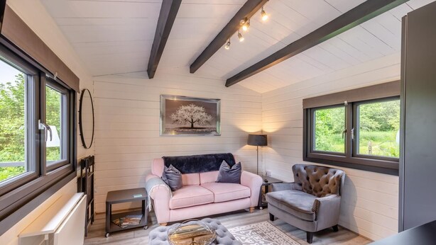 A cozy room with a pink sofa, a grey armchair, a patterned rug, and a framed picture on the wall. - 1 Bed in Wilmington (oc-l31867) (Wilmington)