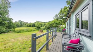 A wooden deck with a bench, a lamp, and a view of a green landscape. - 1 Bed in Wilmington (oc-l31867) (Wilmington)