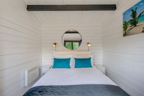 Ein Schlafzimmer mit einem Bett, zwei Nachttischlampen, einem runden Spiegel und einer Wanddekoration zum Strandthema.