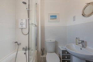 Ein modernes Badezimmer mit einer Glasdusche, einer Toilette und einem Waschbecken mit Spiegel.
